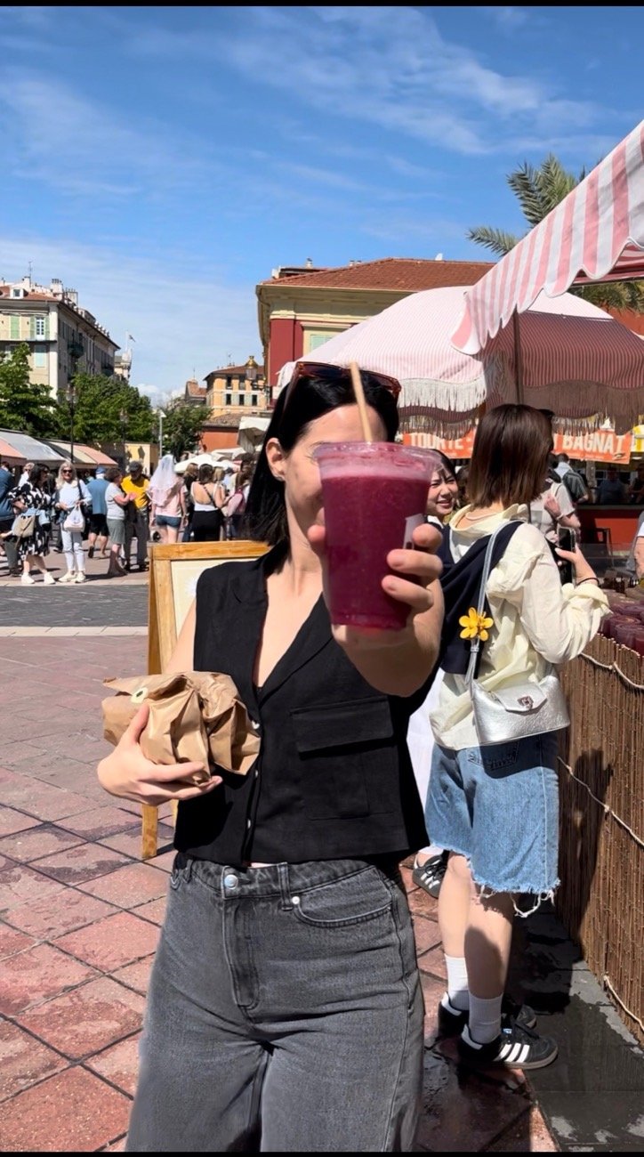 Blandine tend un smoothie vers l'objectif, au marché