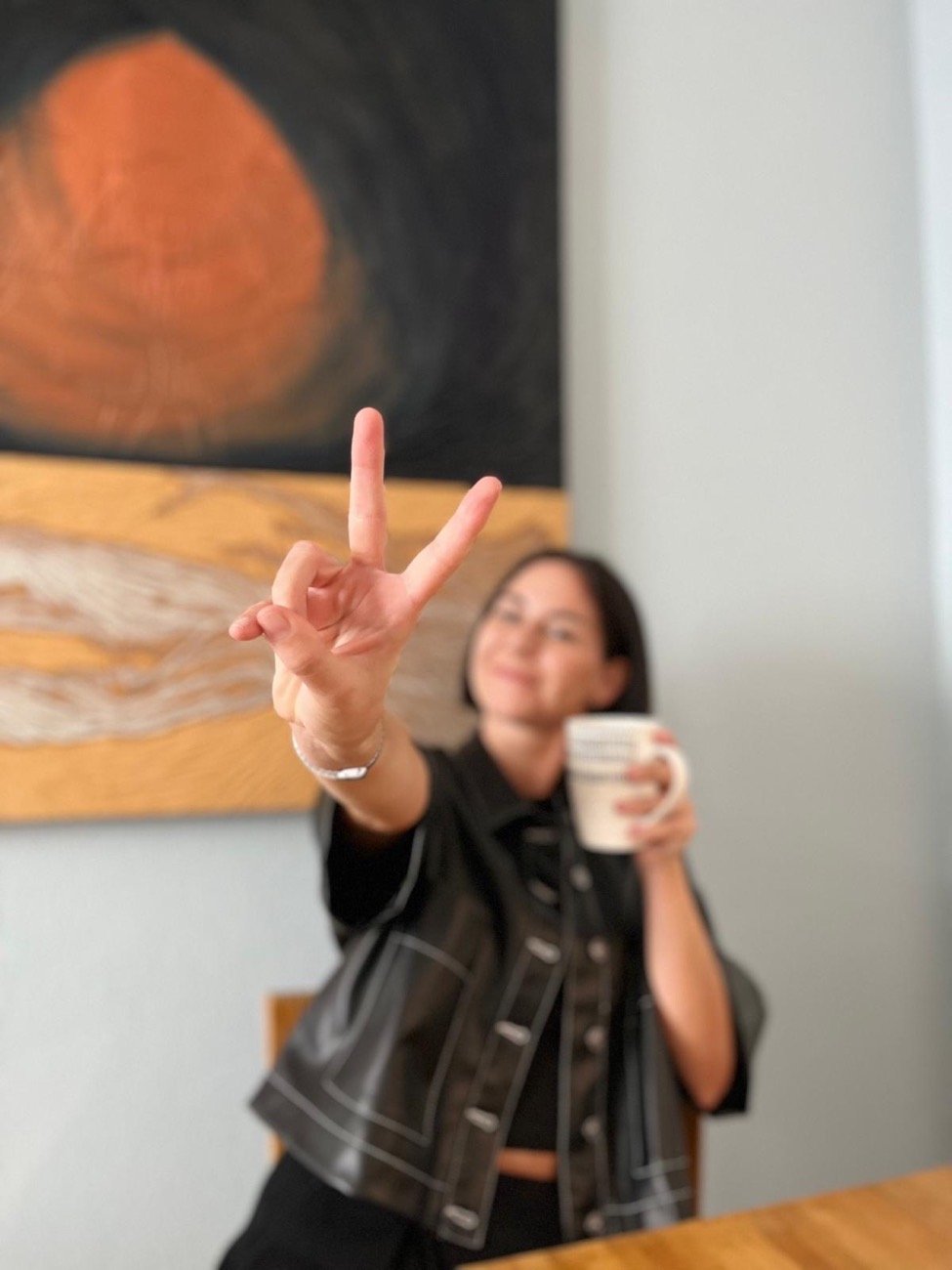Blandine, mug à la main, fait le signe de la victoire