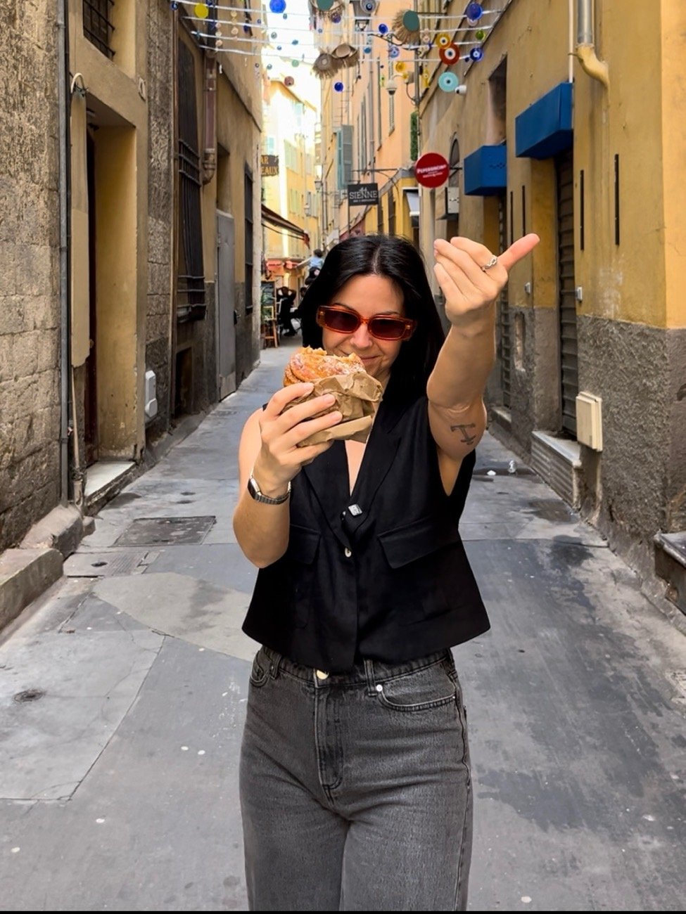 Blandine dans une ruelle du Vieux-Nice, une viennoiserie à la main