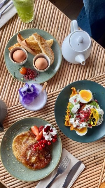 Table de brunch : œufs mouillettes, pancake aux fruits rouges, assiette d'œufs et de feta